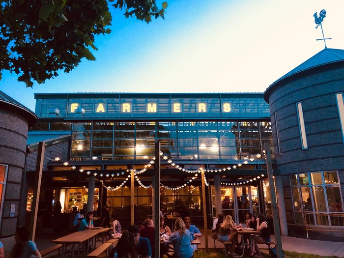 People sit outside at picnic tables at a place called Farmers.