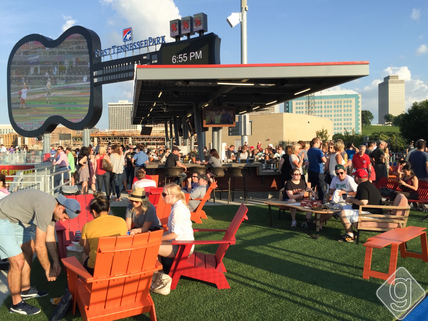 People are gathered outside at a baseball stadium bar.